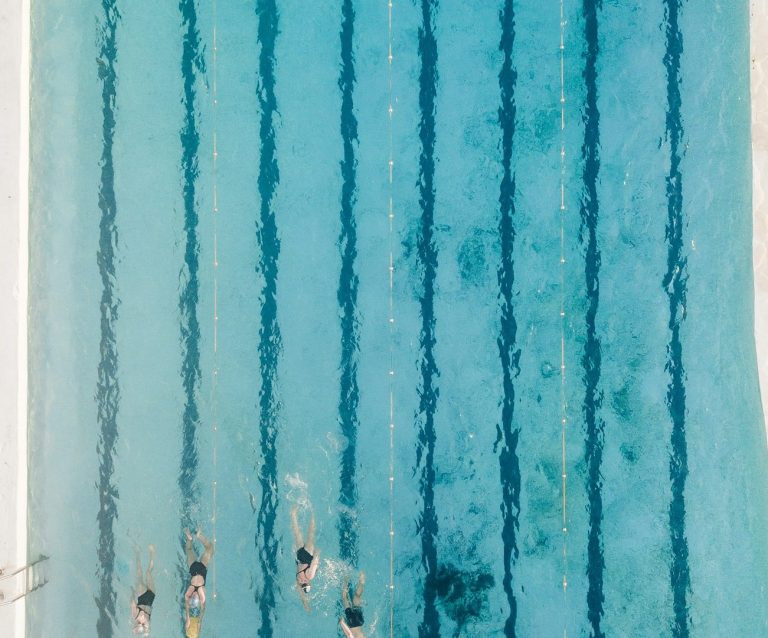 Mehrere Schwimmer in einem klaren, blauem Schwimmbecken mit Linien.