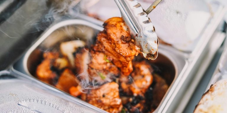 Gegrilltes Hähnchen in einer Servierschüssel mit Tongs.